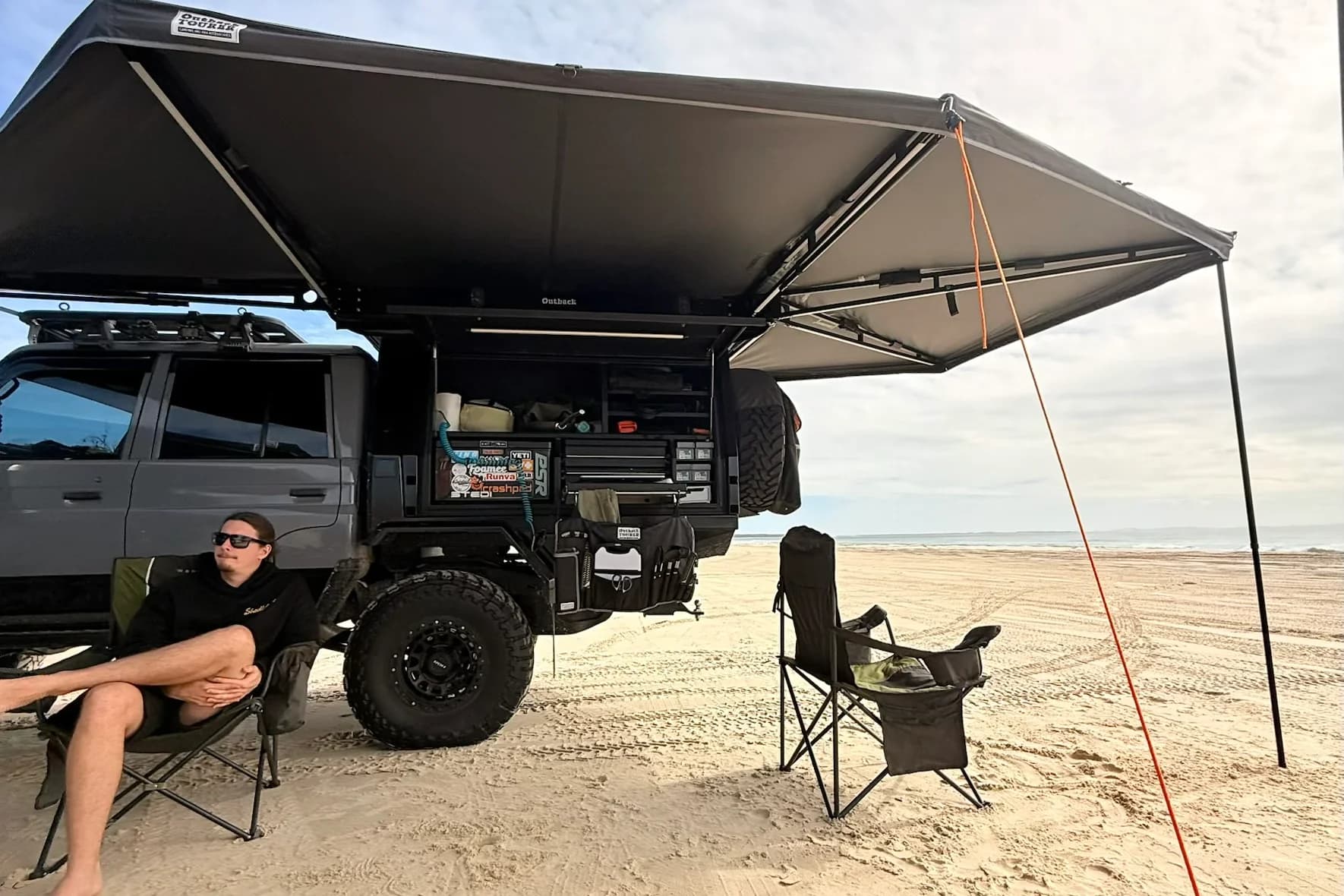 Drewsy's 79 on the beach with the 270 awning out, canopy open and camp chairs set up.