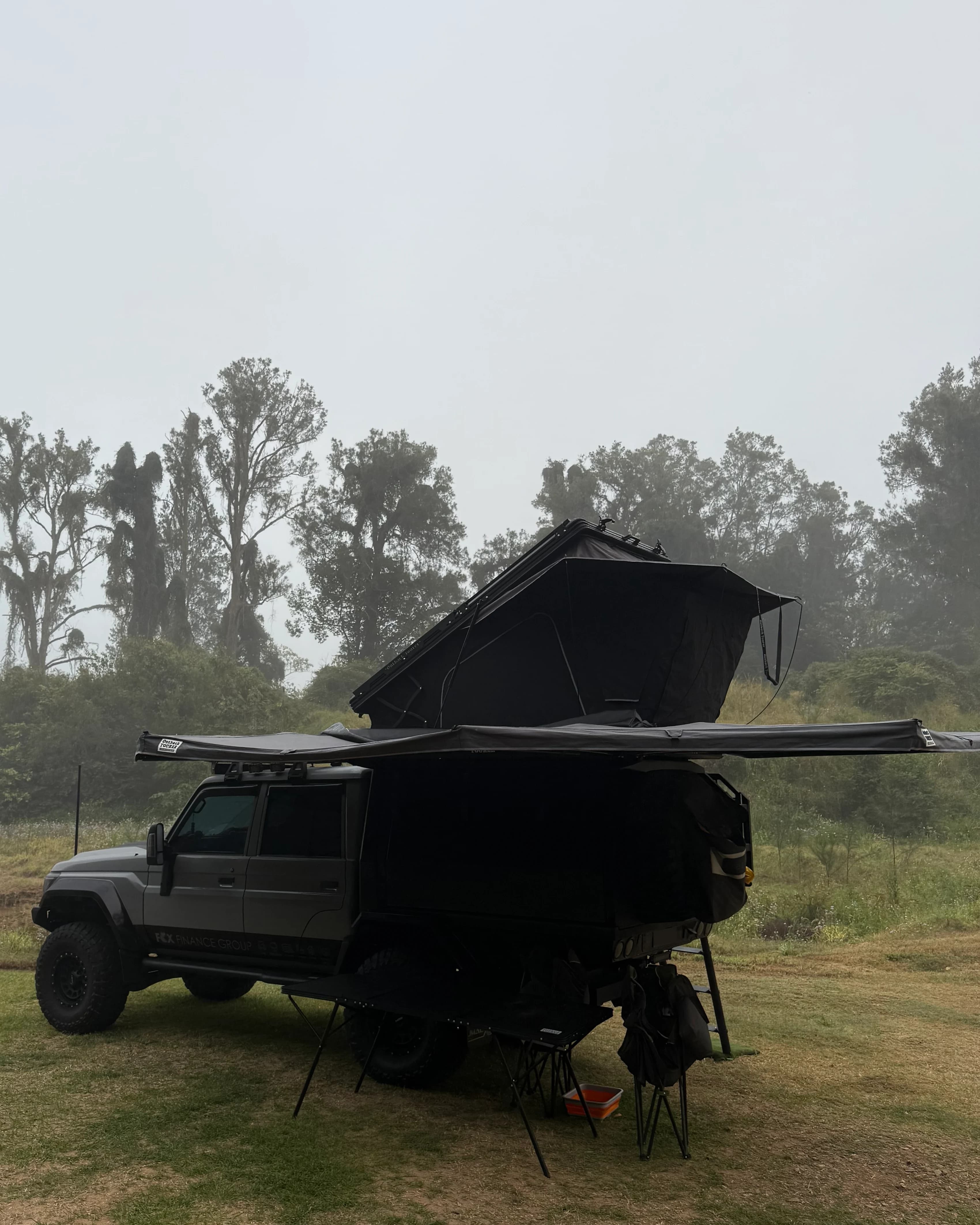 Drewsy's 79 camped in morning fog, rooftop tent open and the awning out.